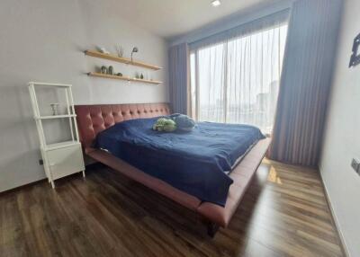 Bedroom with large window, wooden floors, bed, and shelving