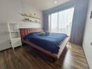 Bedroom with large window, wooden floors, bed, and shelving