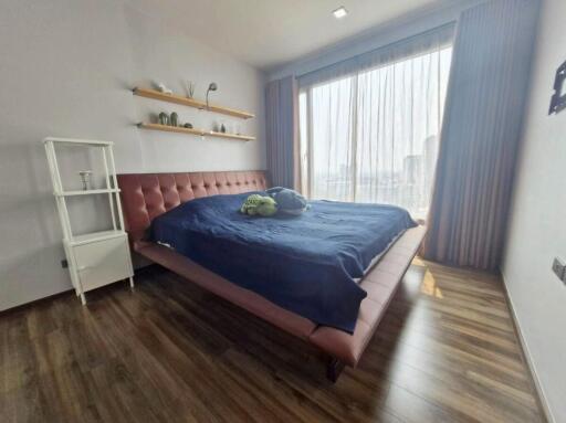 Bedroom with large window, wooden floors, bed, and shelving