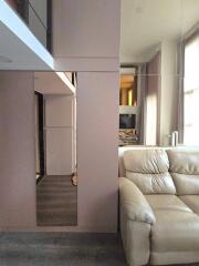 Modern living room with beige leather sofa, large window, and wall-mounted TV