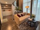 Modern living room with a sofa, glass table, bookshelves, and staircase