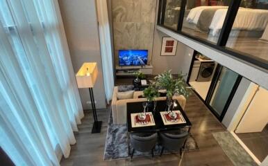 Modern living room with a dining area and a loft bedroom