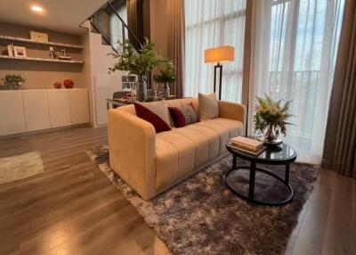 Modern living room with a beige sofa, coffee table, and large windows