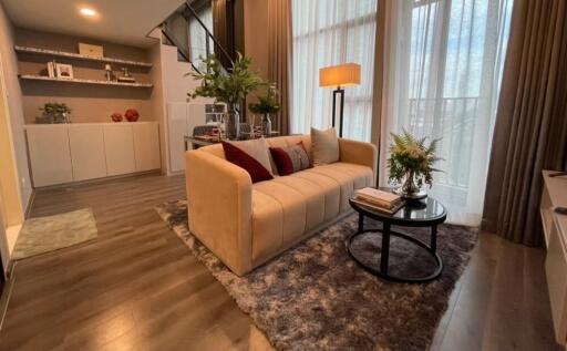 Modern living room with a beige sofa, coffee table, and large windows