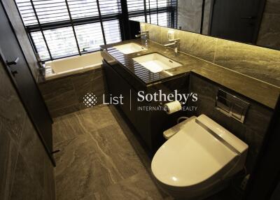 Modern bathroom with bathtub, double sink, and toilet