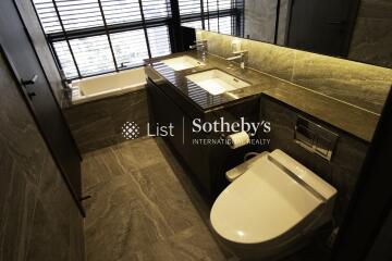 Modern bathroom with bathtub, double sink, and toilet