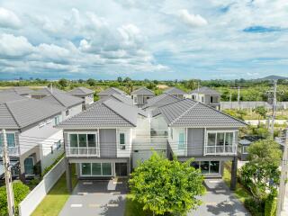 Aerial view of modern suburban houses with grey roofs and green lawns