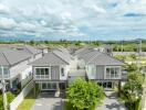 Aerial view of modern suburban houses with grey roofs and green lawns