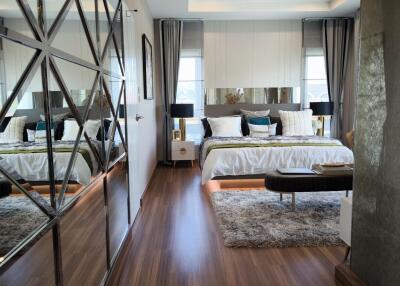 Modern bedroom with large bed, decorative mirror wall, and floor-to-ceiling windows