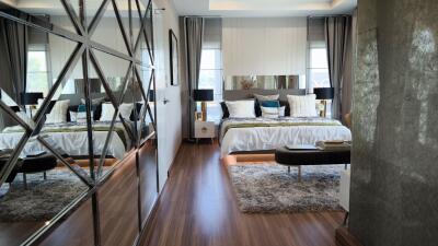 Modern bedroom with large bed, decorative mirror wall, and floor-to-ceiling windows