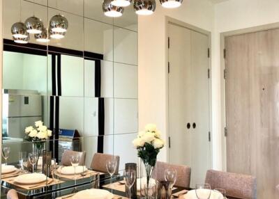 Modern dining room with glass table, beige chairs, and ceiling pendant lights