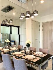 Modern dining room with glass table, beige chairs, and ceiling pendant lights