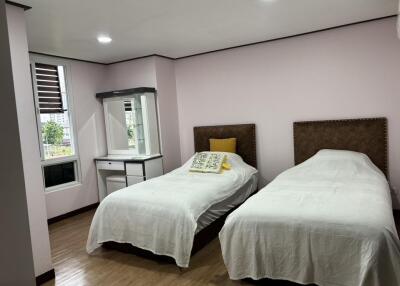 Bedroom with two single beds, a dresser with a mirror, and a window