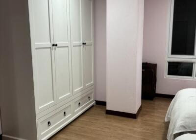 Bedroom with white wardrobe and wooden flooring