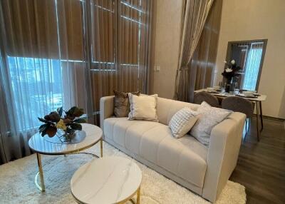 Living room with high ceilings, large windows, sofa, and coffee tables