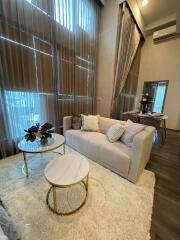 Living room with high ceilings, large windows, sofa, and coffee tables