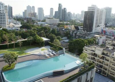 Aerial view of a residential complex with a swimming pool and city skyline in the background