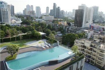 Aerial view of a residential complex with a swimming pool and city skyline in the background