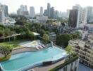 Aerial view of a residential complex with a swimming pool and city skyline in the background