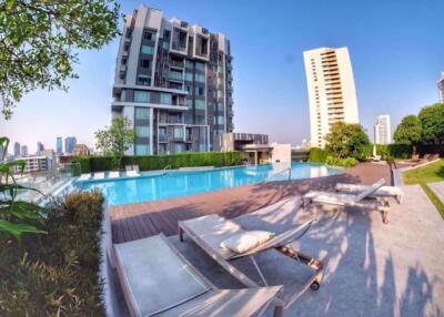 Outdoor pool area with lounge chairs and residential buildings in the background