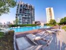 Outdoor pool area with lounge chairs and residential buildings in the background