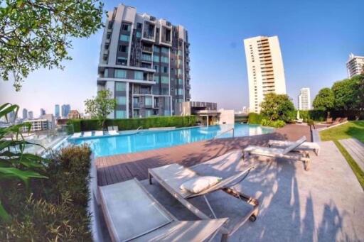 Outdoor pool area with lounge chairs and residential buildings in the background