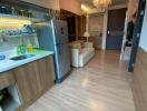 Modern kitchen area with a view into the living space, featuring wood flooring, stainless steel appliances, and a chandelier.