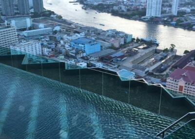 Rooftop view with infinity pool overlooking a city skyline and river