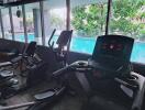 Fitness center with exercise equipment overlooking a pool