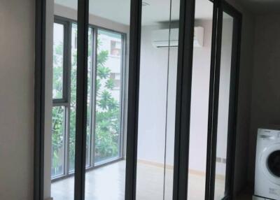 Modern laundry area with floor-to-ceiling glass enclosure and a washing machine