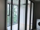 Modern laundry area with floor-to-ceiling glass enclosure and a washing machine