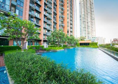 Modern apartment complex with a large swimming pool and greenery