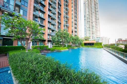 Modern apartment complex with a large swimming pool and greenery