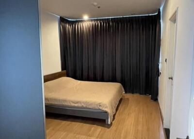 Modern bedroom with wooden flooring and large window with blackout curtains