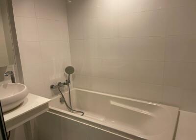 Bathroom with white tiles, bathtub, and sink