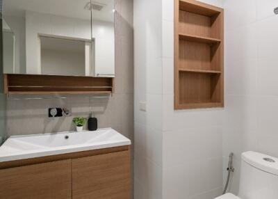 Modern bathroom with vanity, mirror, toilet, and built-in shelving