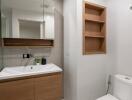 Modern bathroom with vanity, mirror, toilet, and built-in shelving