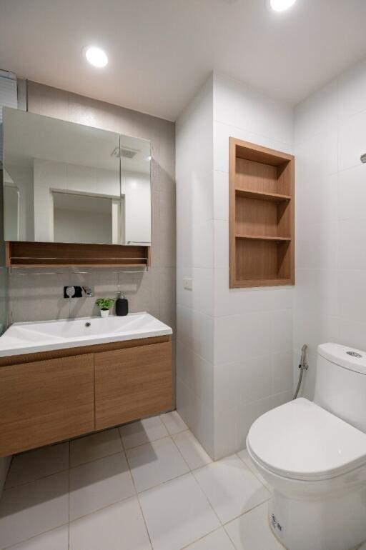 Modern bathroom with vanity, mirror, toilet, and built-in shelving