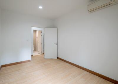 Empty bedroom with wooden flooring and open door to a bathroom