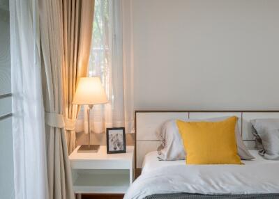 Bedroom with bedside table, lamp and yellow pillow on bed