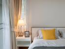 Bedroom with bedside table, lamp and yellow pillow on bed