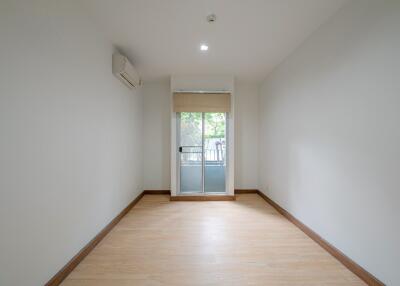 Spacious empty room with wooden flooring, large window, and air conditioning