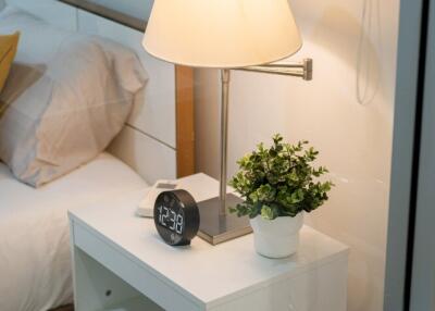 Bedside table with lamp and digital clock in a bedroom