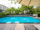 Swimming pool with deck chairs and trees in the background