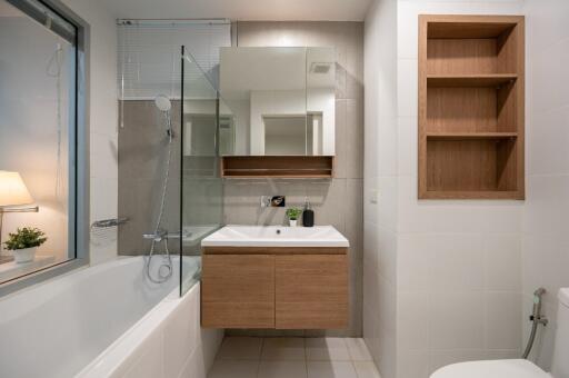 Modern bathroom with a bathtub, shower, sink, and built-in shelves