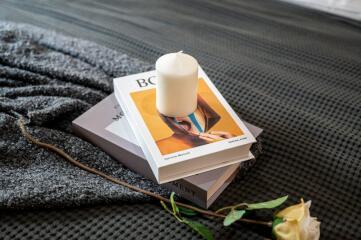 Book with candle on bed