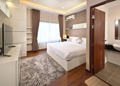 Modern bedroom with hardwood floors, large bed, and en-suite bathroom