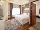 Modern bedroom with hardwood floors, large bed, and en-suite bathroom