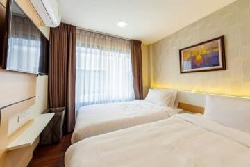 Modern bedroom with twin beds, wall-mounted TV, and framed art