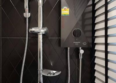 modern bathroom shower with black tiled wall and water heater